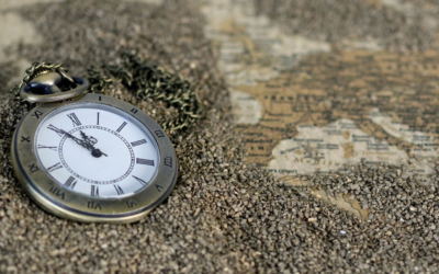 Un orologio da taschino sulla sabbia e una cartina antica